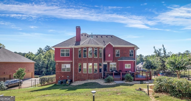 back of house with brick siding, a lawn, a chimney, and fence