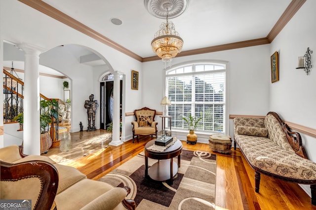 living room featuring ornate columns, crown molding, arched walkways, and wood finished floors