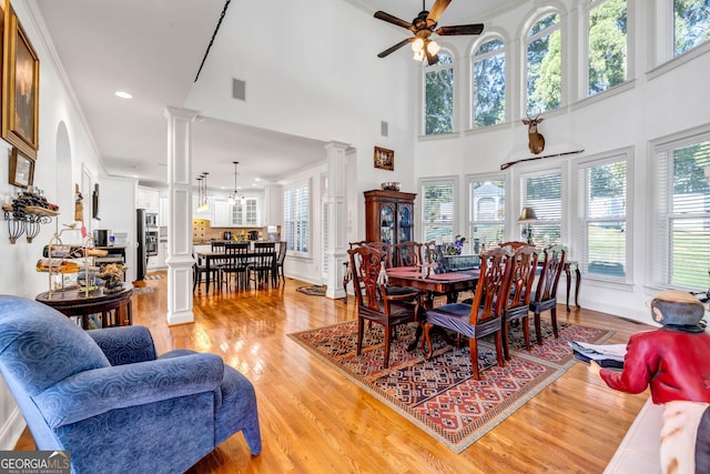 dining area featuring light wood-style floors, decorative columns, plenty of natural light, and ceiling fan