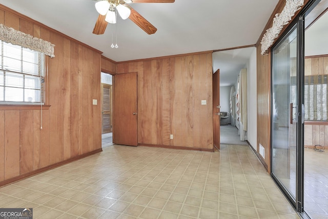 unfurnished room with ceiling fan, ornamental molding, and wood walls