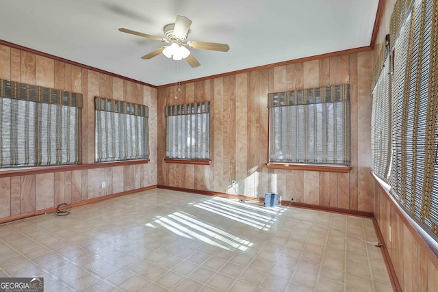 unfurnished room featuring ceiling fan, wooden walls, and ornamental molding