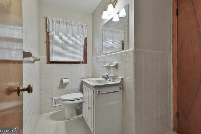 bathroom with toilet, vanity, tile walls, and tile patterned floors