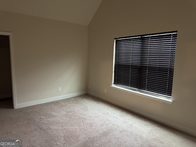 carpeted empty room with lofted ceiling