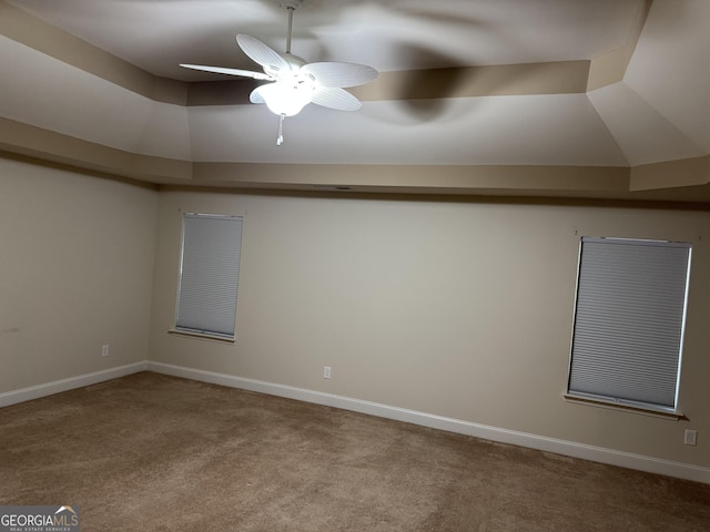 unfurnished room featuring ceiling fan, light colored carpet, and a tray ceiling