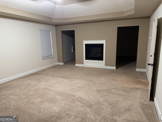 unfurnished living room with light colored carpet and a raised ceiling