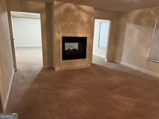 unfurnished living room featuring a multi sided fireplace and carpet floors