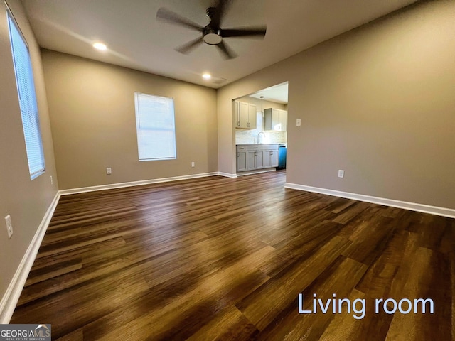 unfurnished living room featuring ceiling fan, dark wood-type flooring, and sink