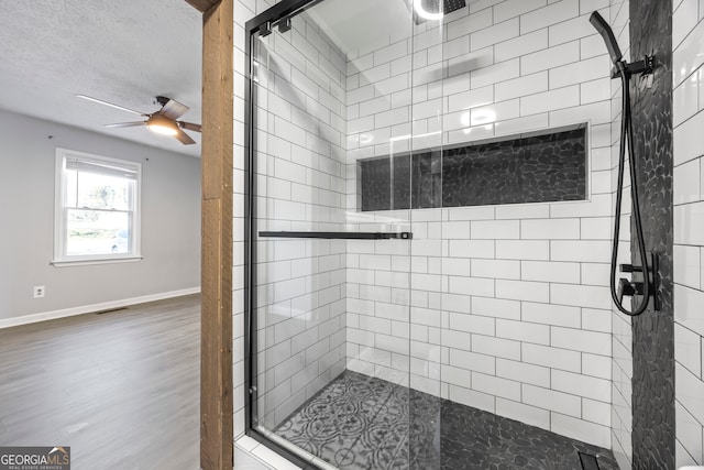 bathroom featuring a textured ceiling, ceiling fan, and a shower with door