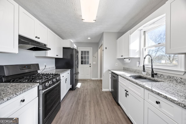 kitchen featuring hardwood / wood-style floors, appliances with stainless steel finishes, light stone countertops, white cabinets, and sink