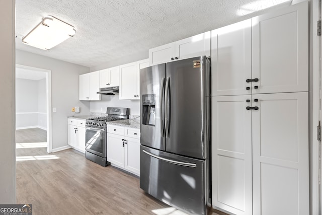 kitchen with light stone counters, light hardwood / wood-style floors, white cabinetry, and appliances with stainless steel finishes