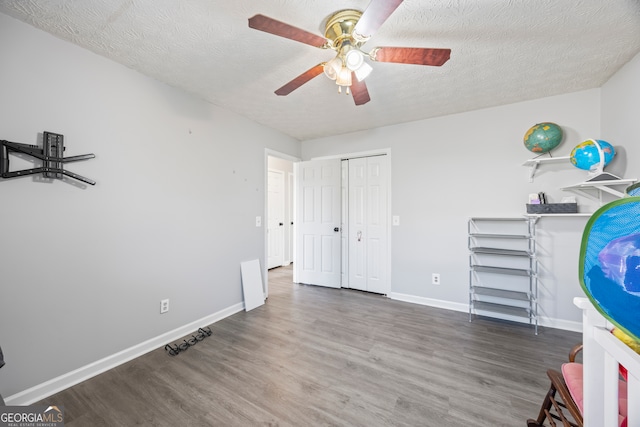 unfurnished bedroom with a textured ceiling, ceiling fan, and dark hardwood / wood-style flooring