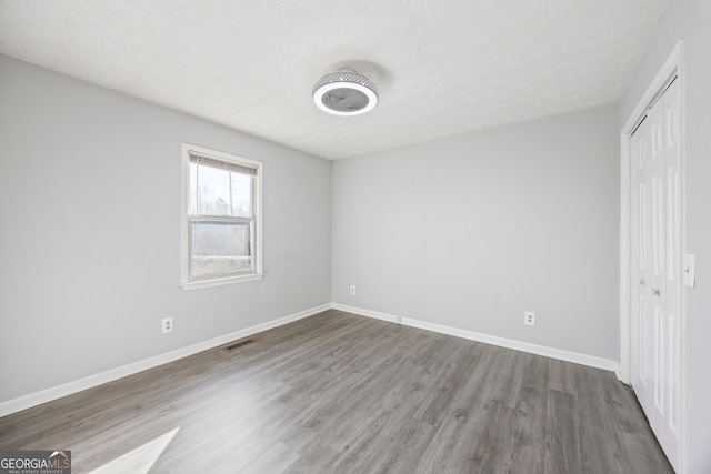 unfurnished bedroom featuring wood-type flooring, a closet, and a textured ceiling