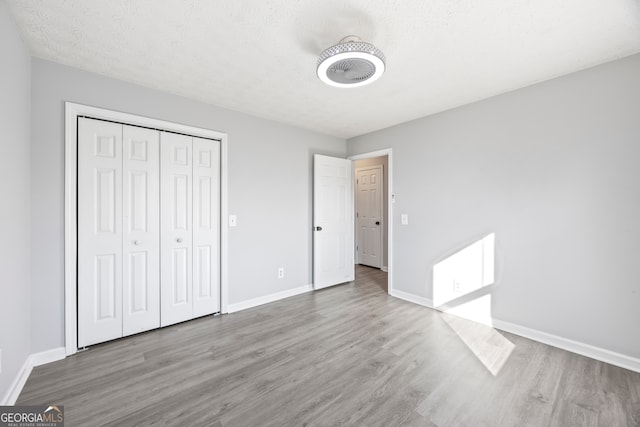 unfurnished bedroom featuring a textured ceiling, a closet, and hardwood / wood-style flooring