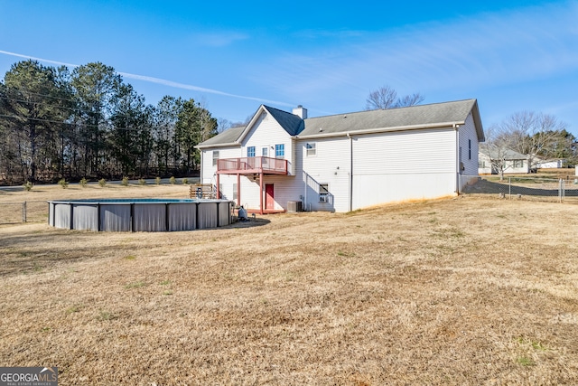 rear view of house with a lawn, cooling unit, and a pool side deck