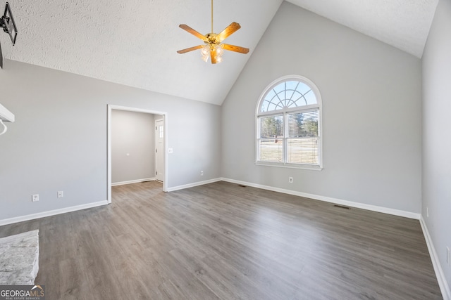 spare room featuring a textured ceiling, dark wood-type flooring, ceiling fan, and high vaulted ceiling