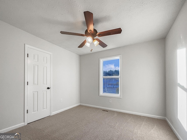 empty room featuring ceiling fan, a textured ceiling, and carpet flooring