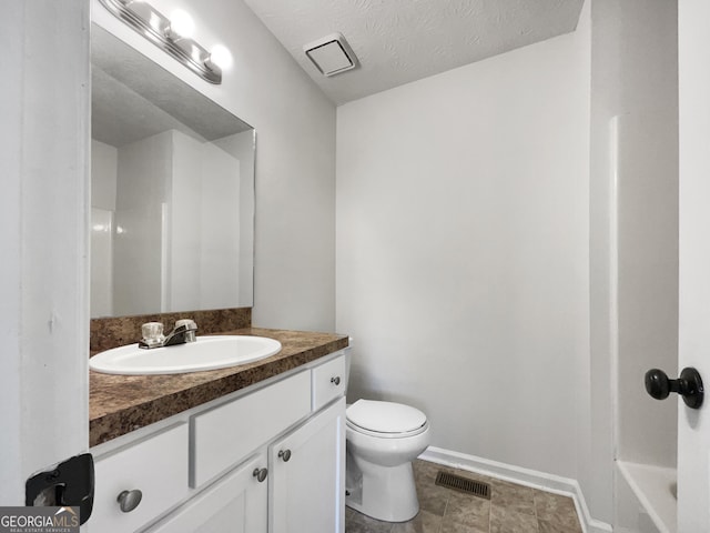 bathroom with toilet, vanity, and a textured ceiling