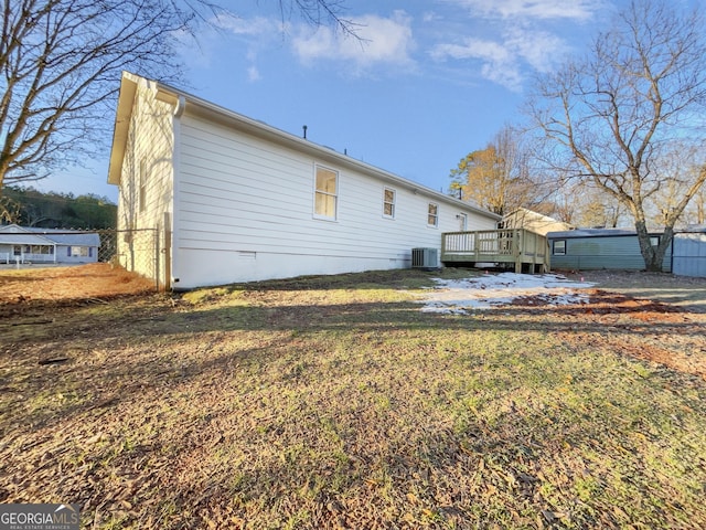 back of property with a deck, cooling unit, and a yard