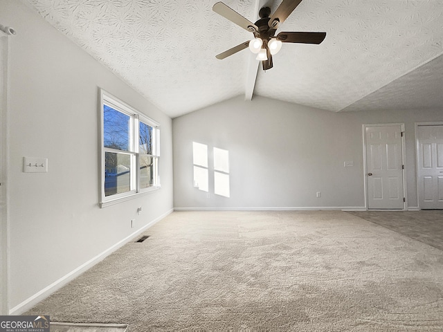 carpeted empty room with ceiling fan, lofted ceiling with beams, and a textured ceiling