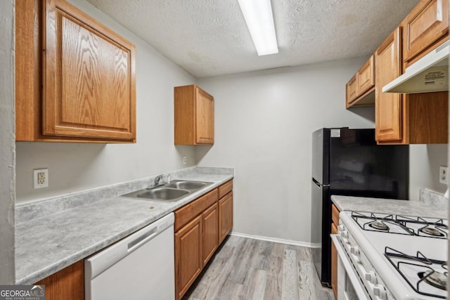 kitchen with sink, white appliances, a textured ceiling, and light wood-type flooring