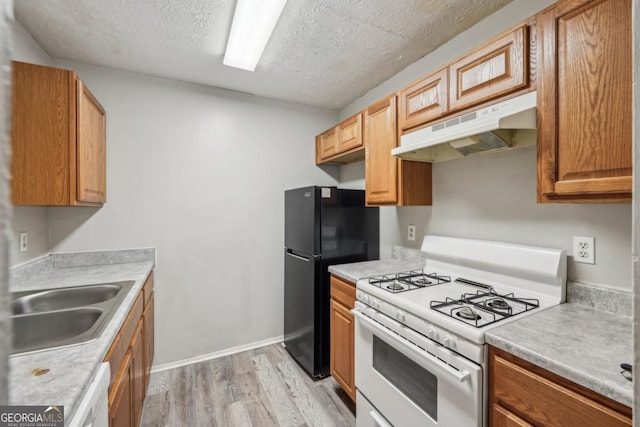 kitchen featuring sink, white appliances, light hardwood / wood-style flooring, and a textured ceiling