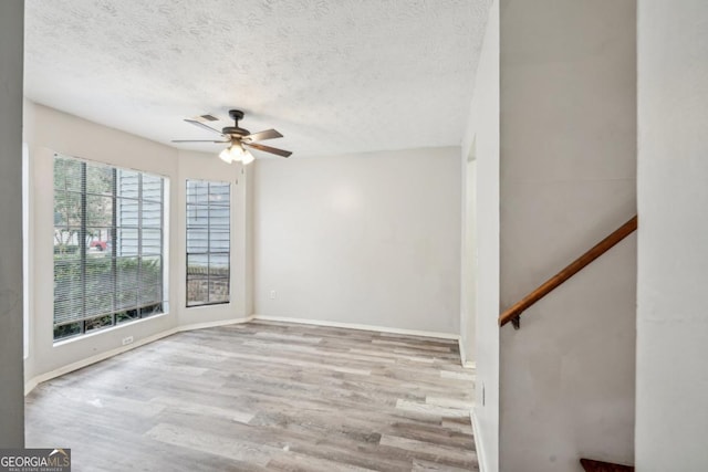 unfurnished room featuring light wood-type flooring, ceiling fan, and a textured ceiling