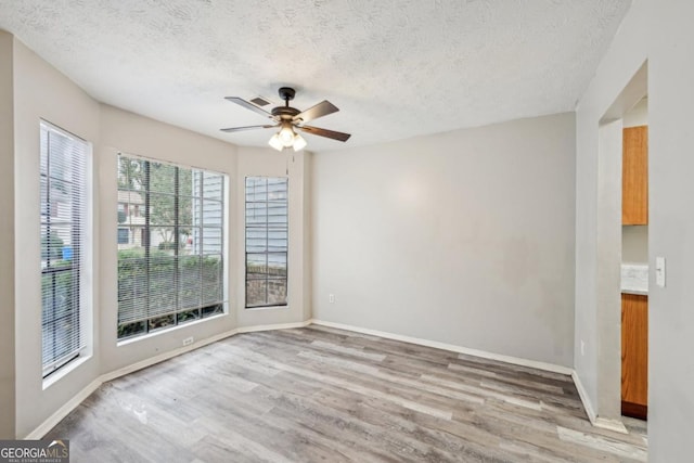 empty room with ceiling fan, plenty of natural light, and light hardwood / wood-style flooring