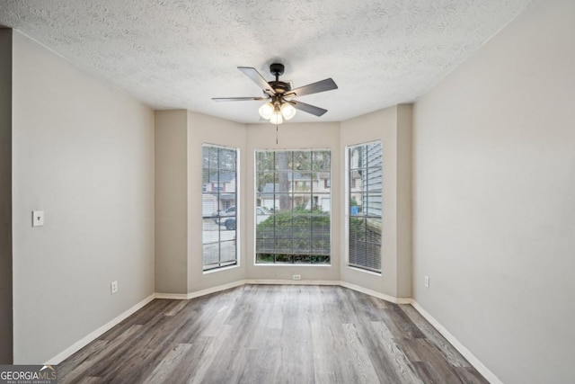 spare room featuring ceiling fan, wood-type flooring, and a textured ceiling