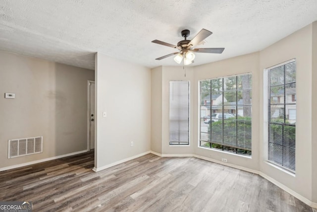 empty room featuring a textured ceiling, ceiling fan, and hardwood / wood-style floors