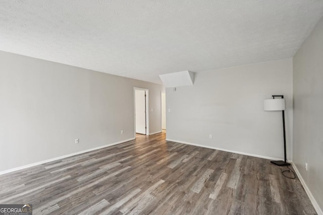 empty room with a textured ceiling and dark hardwood / wood-style floors