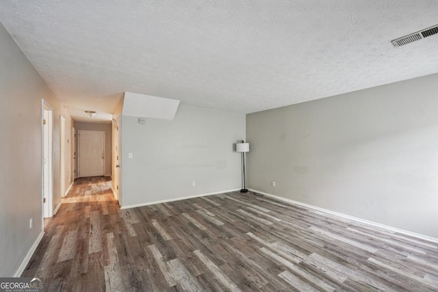 unfurnished room with dark hardwood / wood-style flooring and a textured ceiling