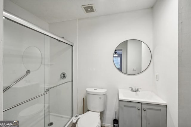 bathroom with toilet, a shower with door, and vanity