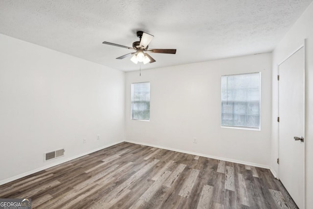 spare room featuring ceiling fan, a healthy amount of sunlight, wood-type flooring, and a textured ceiling