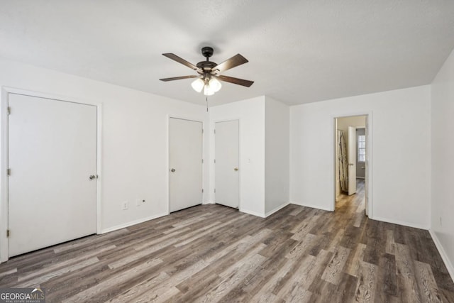 unfurnished bedroom featuring ceiling fan and dark hardwood / wood-style floors