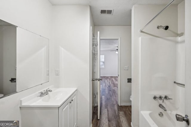 full bathroom featuring toilet, hardwood / wood-style floors, bathtub / shower combination, a textured ceiling, and vanity