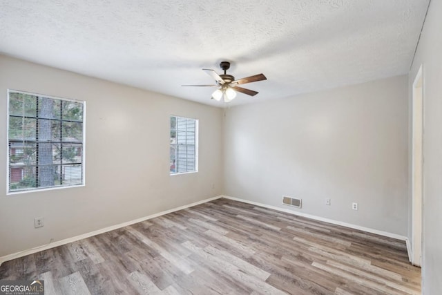 unfurnished room with a textured ceiling, ceiling fan, and light wood-type flooring