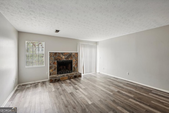 unfurnished living room with a textured ceiling, hardwood / wood-style floors, and a fireplace