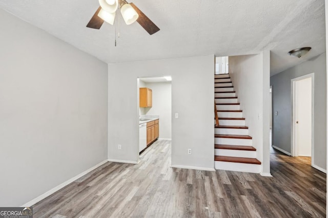 unfurnished living room featuring ceiling fan, wood-type flooring, and a textured ceiling