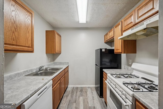 kitchen featuring sink, white appliances, a textured ceiling, and light hardwood / wood-style flooring