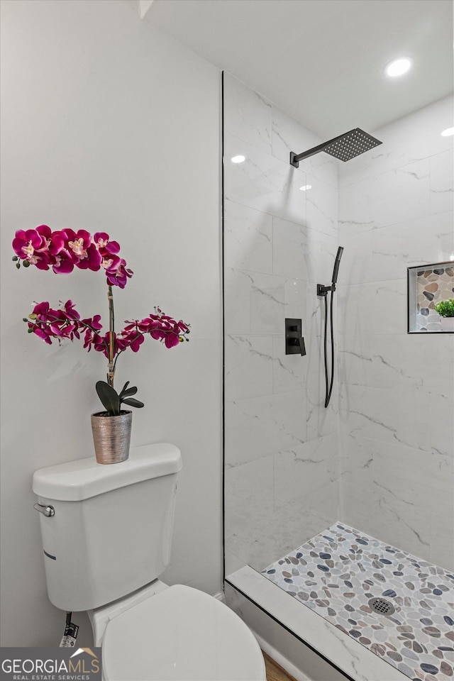 bathroom featuring toilet and a tile shower