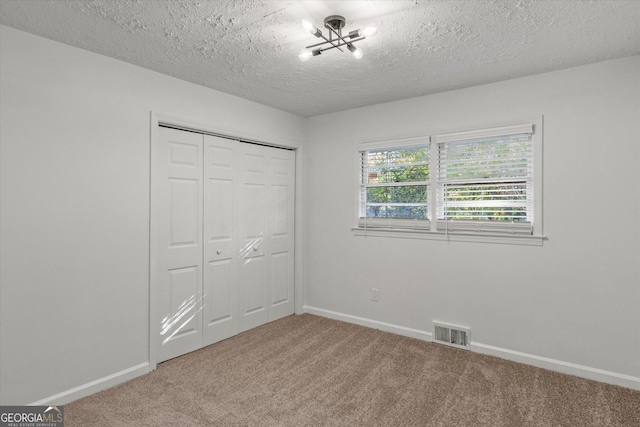 unfurnished bedroom with carpet, a closet, and a textured ceiling