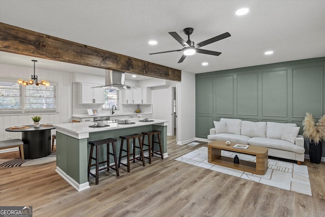 living room with ceiling fan with notable chandelier, a textured ceiling, sink, light wood-type flooring, and beam ceiling