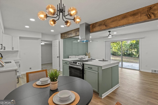 kitchen featuring a center island, electric range, white cabinets, island range hood, and ceiling fan with notable chandelier