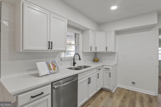 kitchen with tasteful backsplash, dishwasher, sink, white cabinetry, and light stone counters