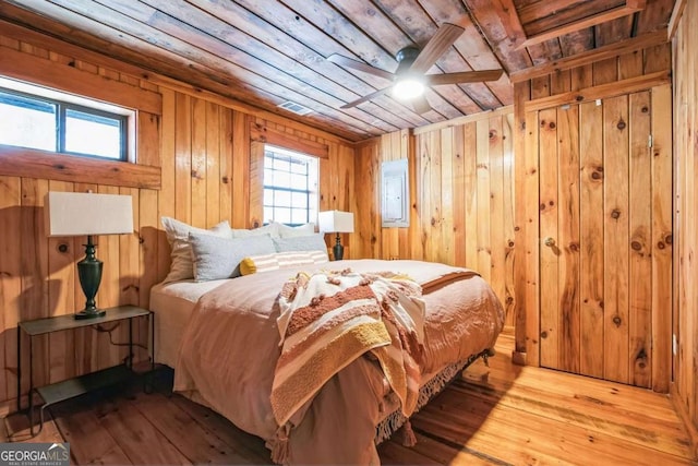 bedroom featuring ceiling fan, wooden ceiling, light hardwood / wood-style floors, and wooden walls