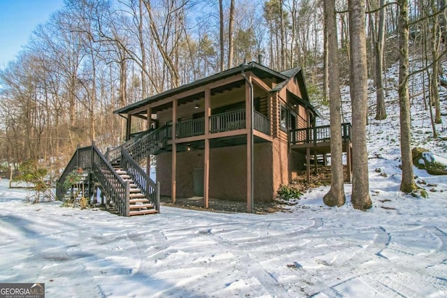 snow covered back of property featuring a deck