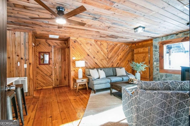 living room with ceiling fan, wooden ceiling, hardwood / wood-style floors, and wooden walls