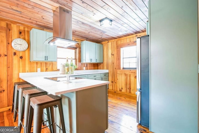 kitchen with wood ceiling, a kitchen breakfast bar, wood walls, island range hood, and kitchen peninsula