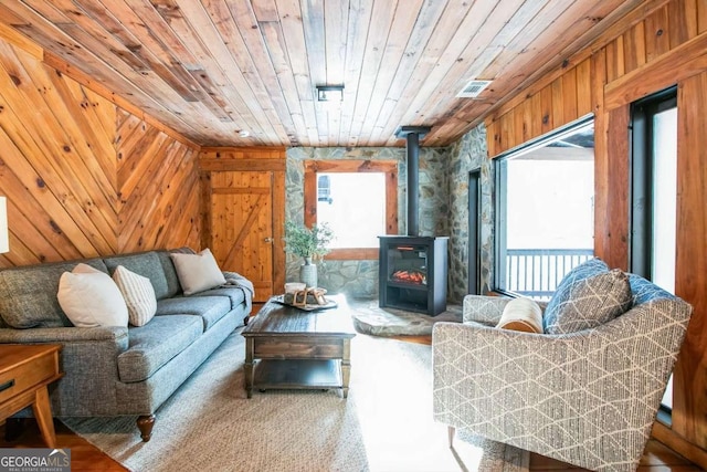 sitting room with wood ceiling, wood walls, and a wood stove