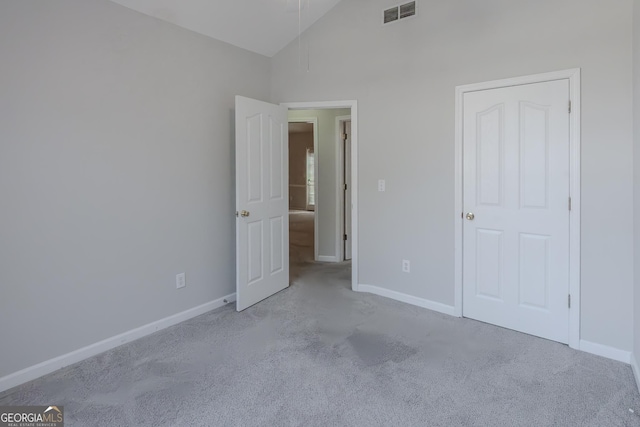 unfurnished bedroom featuring light carpet and high vaulted ceiling